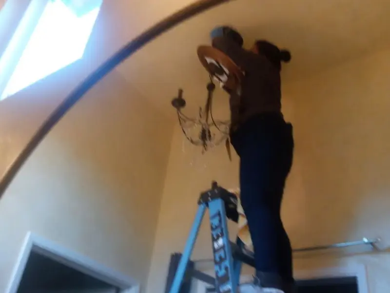 Electrician installing a chandelier in a Irondale residence